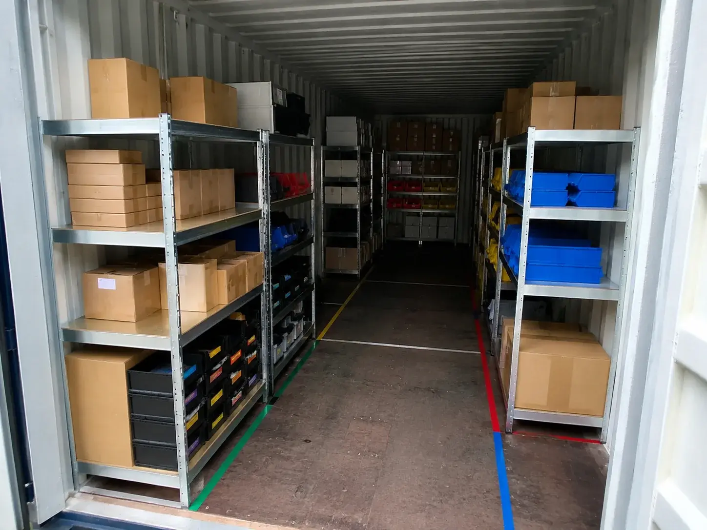 Ordentlich beschriftete Regalfächer und Zonen im Innenraum eines Lagercontainers