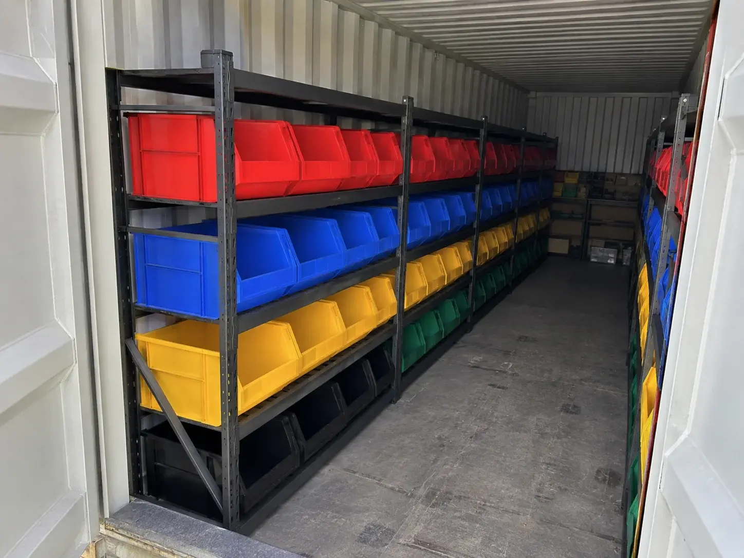 Farblich sortierte Kleinteilekästen auf Regalböden im Lagercontainer