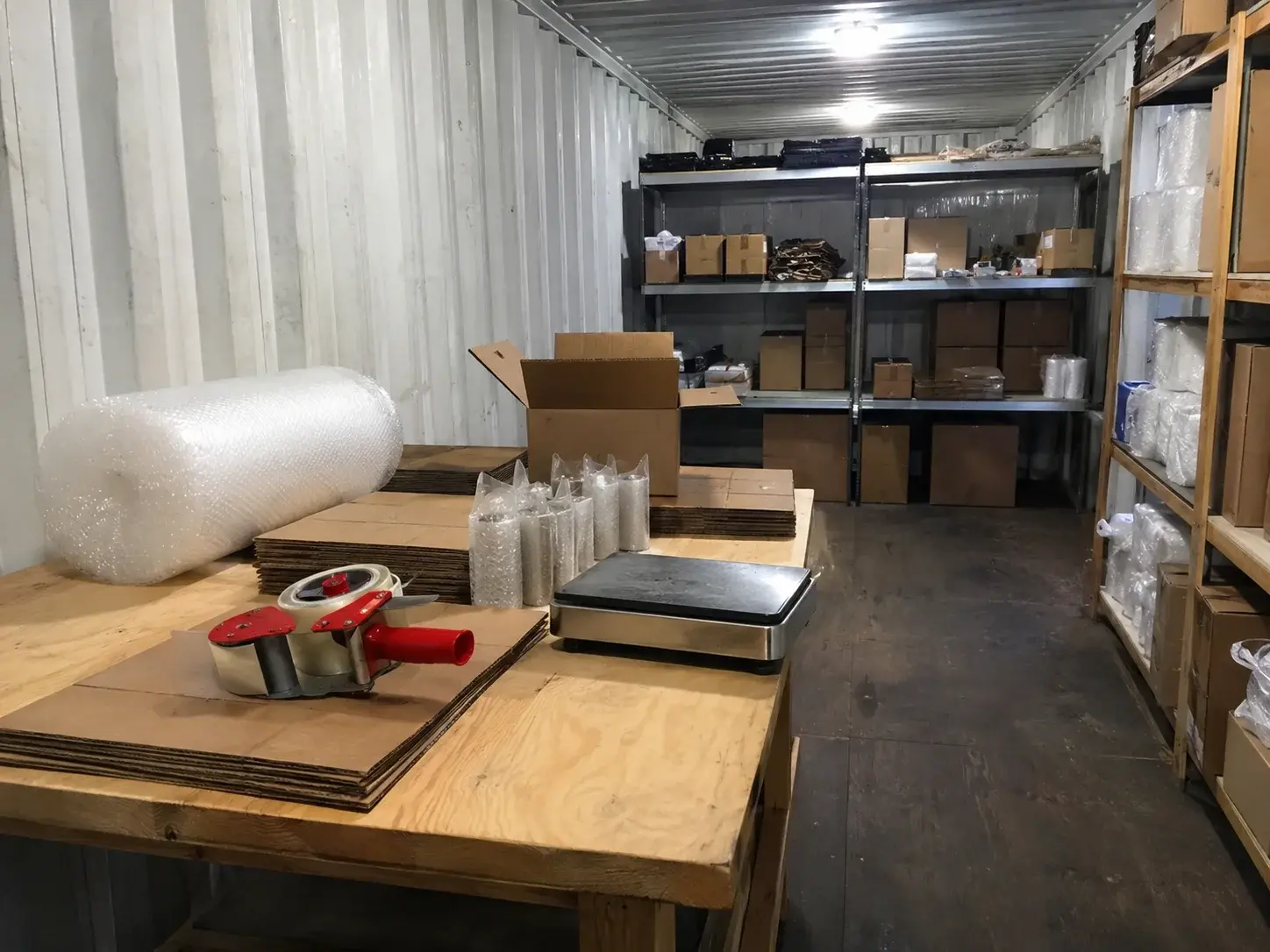 Packplatz mit Arbeitstisch und Versandmaterial im Lagercontainer