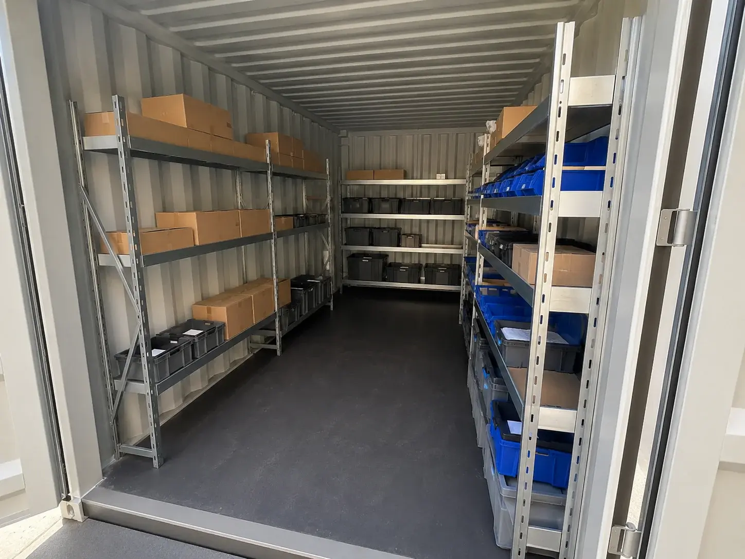 Innenraum eines Lagercontainers mit Fachbodenregalen voller beschrifteter Kartons